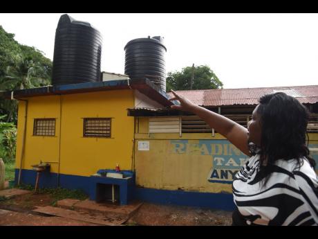 Credit: Ian Allen/Photographer Luleeta Peters, principal of Springvale Primary School in St Catherine, points to water storage tanks that serve the institution.