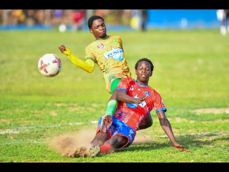 Credit: Matthew McKoy Romaine Tomlinson (right) of Holy Trinity High puts in a strong tackle on Jaheem Darby of St .Jago High during their Manning Cup match at Holy Trinity yesterday. St Jago won 2-0.