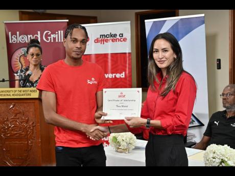 Credit: Rudolph Brown Joelle Fontaine (right), corporate marketing manager of CB Group, presents the CB Group UWI scholarship to Thrion Mitchell, Faculty of Social Sciences, Banking and Finance, on Monday.