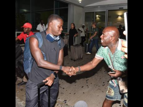 Oblique Seville (left) is greeted by a fan on Wednesday night on his arrival at the Norman Manley International Airport in Kingston from the World Athletics Championships, held in Tokyo, Japan, where he won gold in the men’s 100m.
