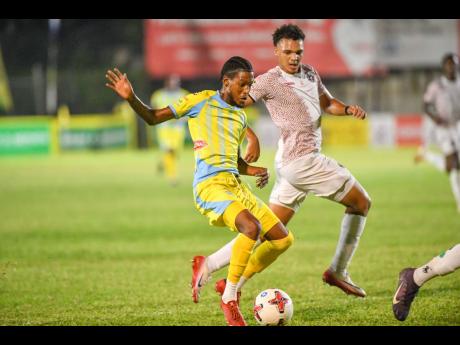 Shamarie Dallas (left) of Waterhouse runs with the ball while Dante Peralto of Chapelton Maroons reacts during the Jamaica Premier League football match at Drewsland Mini Stadium in Kingston last night. Waterhouse won 3-0.