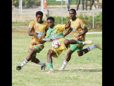 Credit: Ian Allen Kimarly Scott (centre) of Excelsior High is tackled by
St Jago High’s Jordon Taylor (left) during their ISSA Manning Cup match at the Courtney Walsh Oval yesterday. The game ended 0-0.