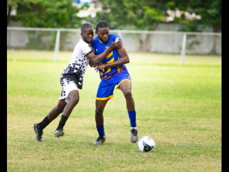 Credit: Contributed RJRGLEANER’s Kennario Henry (right) is fouled by a Jamaica Customs opponent as he looks to play the ball during the KSAFA Business House football preliminary round match against Jamaica Customs at Winchester Park, St. George’s College. RJR GLEANER will tackle defending champions NHT in tomorrow’s final at Ashenheim Stadium, Jamaica College.