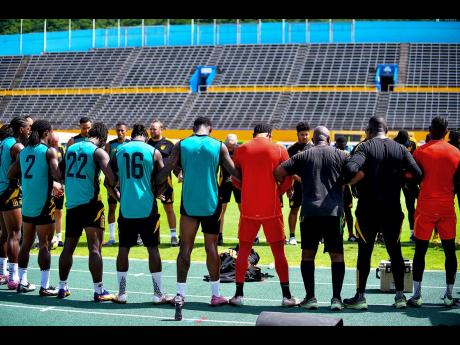 Credit: Matthew McKoy Reggae Boyz and members of the coaching staff huddle before a training session at the National Stadium yesterday.