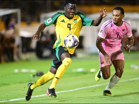 Credit: Gladston Taylor Jamaica’s Kaheim Dixon (left) powers past LeJuan Simmons of Bermuda during last night’s Concacaf Group B World Cup Qualifying match at the National Stadium. Jamaica won 4-0.