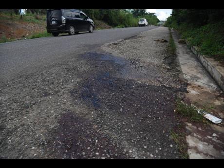 Credit: Ian Allen Bloodstains mark the spot where gunmen were cut down by the police in a gunfight along the Linstead Bypass in St Catherine on Monday night.