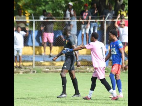 Credit: Ashley Anguin Kemps Hill High School’s goalkeeper Omario Chambers (centre) gesticulates as he argues with referee Obrian Warren (left) during the ISSA WATA daCosta Cup round-of-16 football match against St Elizabeth Technical High School (STETHS) at STETHS yesterday. Looking on is Kemps Hill’s Orlando Campbell. STETHS won 4-0.