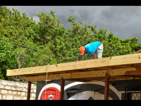 Mark Daley fixes his roof at Black Beard Pub on New Street in Port Royal on Thursday.