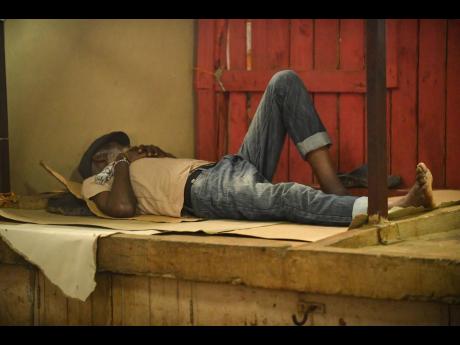 Credit: Photo by Matthew McKoy This man makes himself comfortable in Coronation Market in downtown Kingston yesterday as vendors say they are staying put despite the storm.