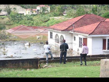 Credit: Ian Allen Onlookers observe houses and motor vehicles submerged along Gibson Close in Mandeville, Manchester, during the passage of Hurricane Melissa.