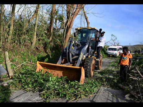 Credit: Gladstone Taylor Heavy-duty machinery is used to remove fallen trees, uprooted poles, and other debris blocking the roadway in Lacovia, St Elizabeth, as crews work to reopen access after Hurricane Melissa.