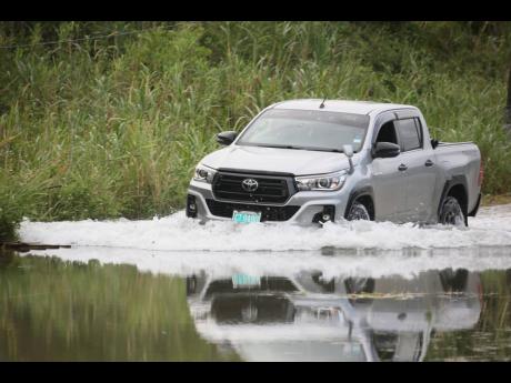Credit: Nathaniel Stewart A vehicle struggles through a flooded road in Content, near Williamsfield, Manchester, where rising groundwater has submerged several homes and left the roadway nearly impassable.