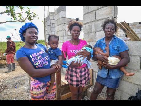 From left: Shauna-Kay McFarlane cradles her daughter Milliana, while her sister Cherry-Ann McFarlane holds her son Theo. Their mother, Denise Miller, holds her grandson Knackary in front of a house under construction in Bybrooks, St Elizabeth.