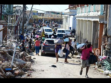 Credit: Gladstone Taylor/Multimedia Photo Editor Persons make their way along Crane Road in Black River, St Elizabeth, carrying much-needed supplies.