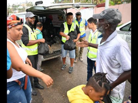 Credit: Antwaine Campbell Chairman of the St. James Municipal Corporation and Mayor of Montego Bay, Councillor Richard Vernon (second from left), joins members of the Chinese community in distributing care packages to residents in Green Pond, St James, recently.