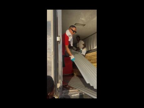 Credit: Contributed Rohan Melhado (left), entrepreneur and music producer, helps to offload building material to residents displaced by Hurricane Melissa.