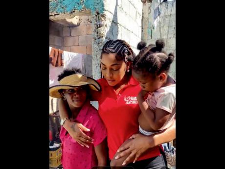 Dancehall artiste D’Angel (centre) during her visit to assist single mother of five, Chuddian Williams (left), and her three-year-old daughter, Leanna Miller, at their home that was destroyed by the Category 5 Hurricane Melissa on October 28, 2025.