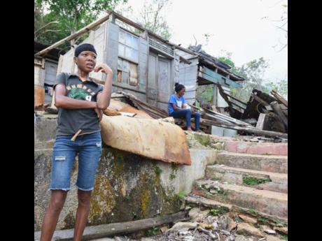 Credit: Ian Allen Theressa Smith stands outside what is left of her three-bedroom home in Troy, Trelawny. Her mother Julie sits close to the dwelling.