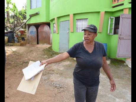 Credit: Ian Allen Cynthia Watt surveys her yard, devastated after the temporary road cut through her land following Hurricane Melissa.