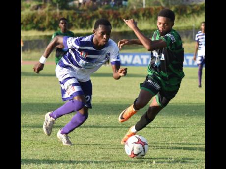 Credit: Ian Allen Kajay Fletcher (left) of Kingston College and Calabar High School’s Payton Larmond challenge for the ball during their ISSA WATA Manning Cup football match at Stadium East yesterday. The match ended 2-2.