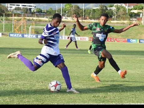 Kajay Fletcher (left) of Kingston College looks to shoot while Payton Larmond of Calabar High positions to block during their ISSA WATA Manning Cup football match at Stadium East field on Wednesday. The game ended 2-2.