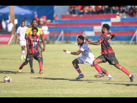 Ronaldo Robinson (second right) of Portmore United runs toward the ball with Roderick Granville of Arnett Gardens close behind during the Jamaica Premier League football match at Ferdi Neita Park, St Catherine, yesterday. Portmore
won 1-0.
