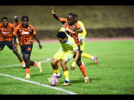 Credit: Matthew McKoy Mario Simms (centre) of Waterhouse FC tries to keep the ball away from Tkiven Garnett (second right) of Tivoli Gardens and his teammates during the Jamaica Premier League football match at Stadium East yesterday. Tivoli won 2-1.