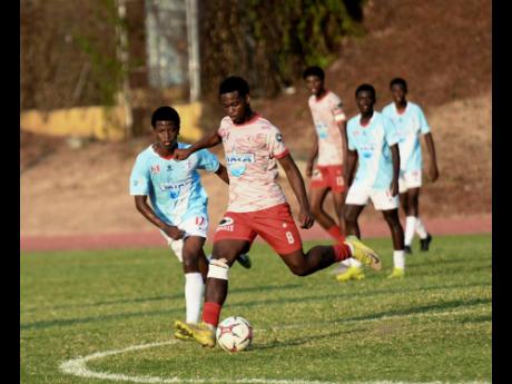 Credit: Antoine Lodge Javade Wallace of Mona High School (second left) looks to kick the ball as Malik Garriques (left) of St George’s College reacts during the Walker Cup KO football match at Stadium East yesterday.