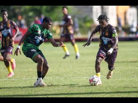 Credit: Matthew McKoy Kevin Hall (right) of St Andrew Technical High School (STATHS) dribbles the ball, while Keneal Peters of Calabar High looks to defend during the ISSA WATA Manning Cup football match, at Stadium East on Tuesday. STATHS won 4-1.