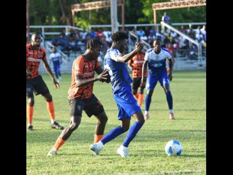 Credit: Ashley Anguin Mount Pleasant Football Academy’s Daniel Green (centre) shields the ball from Tivioli Gardens FC’s Denville Watson during their Jamaica Premier League football game at Drax Hall Sports Complex on Thursday. Mount Pleasant won 5-0.