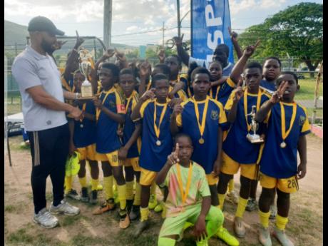 Credit: Livingston Scott Balmagie Primary School captain, leading scorer and the competition’s MVP, Kevin Grant receives the Insports St Andrew Primary Schools Football trophy from Insports officer Sylvester Campbell (left) following the final against St. Richards Primary at UWI Bowl, Mona on Friday. Balmagie won 4-3 on penalties after playing to a 0-0 draw.