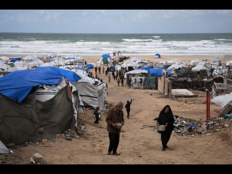 Palestinians receive donated food at a temporary camp for displaced people, on the beach near the port of Gaza City, on Sunday.