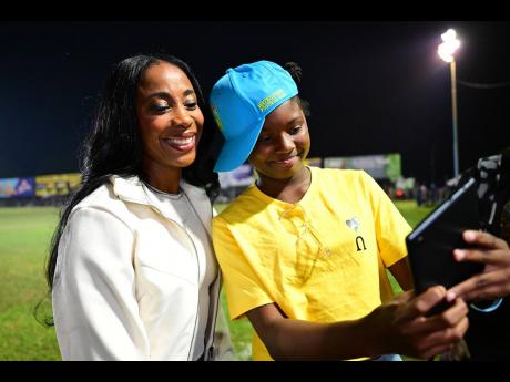 Amoya McBean (right), sporting her Waterhouse FC cap takes a photo with Shelly-Ann Fraser-Pryce at the Waterhouse Mini Stadium in Drewsland on Sunday. Fraser-Pryce was presented with a citation as part of the recognition by the football club.