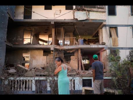 Credit: Matias Delacroix Residents look at a damaged apartment complex that neighbours say was hit during US strikes to capture Maduro, in Catia La Mar, Venezuela.