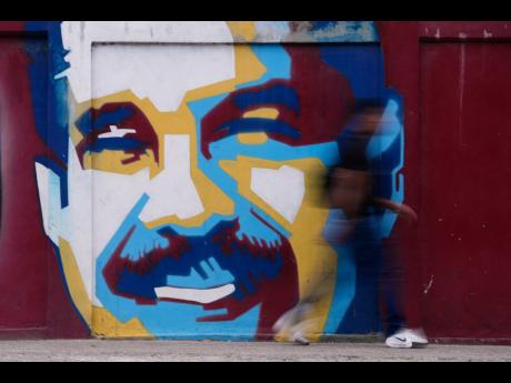 Credit: Matias Delacroix A pedestrian walks past a mural of Venezuelan President Nicolas Maduro.