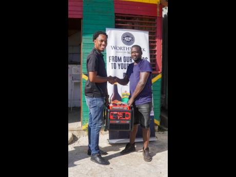 Credit: Contributed Janoi Cunningham (left), Worthy Park’s trade developer, hands over a generator to Aubrey Stone, of Stone’s Fruits & Bar, in Oxford, St Elizabeth.