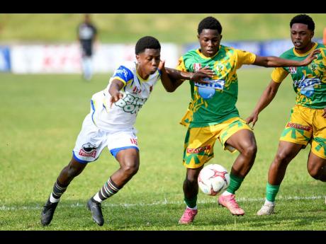 Raheim Whyte (left) of St Elizabeth Technical High School fights for the ball with Kevin Deacon (centre) of Excelsior High School during the Olivier Shield title showdown at Stadium East in Kingston on Thursday. Excelsior won 2-0.