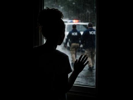 In this AI-generated image, Jane* stands at a window watching ICE agents outside, symbolising the fear and uncertainty faced by undocumented immigrants as court hearings approach and the threat of deportation looms.