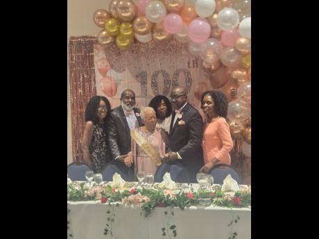 Centenarian educator Henrietta Williams beams with joy as family members surround her on her 100th birthday.