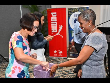 Credit: Rudolph Brown Simone Foote (left), marketing manager of BPM Financial Ltd, and Genevieve Reid prepare the pot for sponsors to draw events during the launch of the Gibson McCook Relays at The Jamaica Pegasus hotel in New Kingston yesterday.