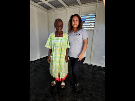 Eugenia Nembhard, 92, shares a quiet moment with Michelle Williams, regional director of VP Records, outside the one-bedroom house gifted to her through the S Hotel Foundation.