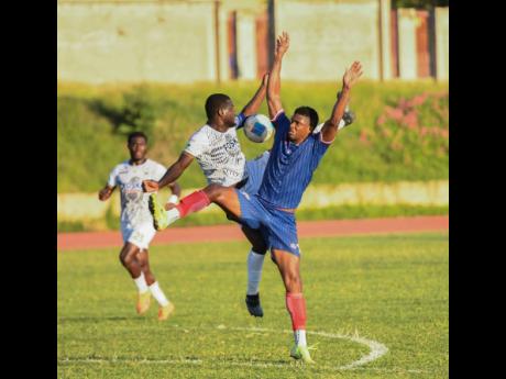 Jeovanni Laing (centre) of Cavalier FC and Andre Clennon (right) of Spanish Town Police FC challenge for the ball during the Jamaica Premier League football match at Stadium East on Monday. Cavalier won 5-0.
