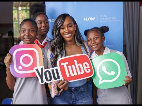 Social media influencer Tanaania Tracey (centre) poses with students of The Queen’s School during a Flow Safer Internet Day activation at the St Andrew-based school yesterday.