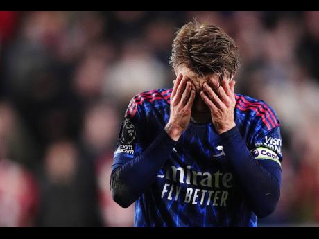 Arsenal’s Martin Odegaard reacts after getting injured attempting to prevent Brentford’s Keane Lewis-Potter from scoring during the English Premier League soccer match in London on Thursday.