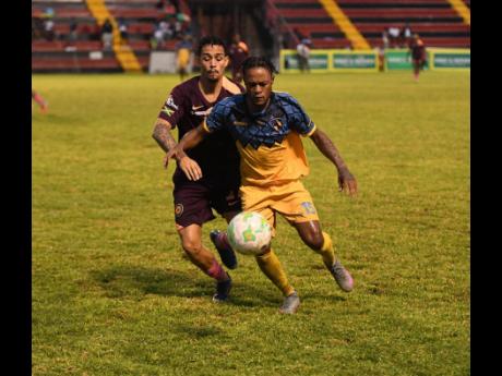 Mikyle Williams of Racing United FC (right) controls the ball as Marcos Filho of Chapelton Maroon FC approaches during the Jamaica Premier League football match at the Anthony Spaulding Sports Complex in Kingston yesterday. Racing were 2-0 winners.