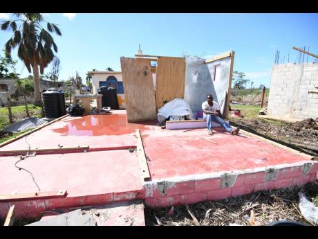 Credit: Antoine Lodge Parrottee resident Owen Smith sits on the floor of what was his home, which was destroyed by Hurricane Melissa last October. The home also suffered damage in 2024 during the passage of Hurricane Beryl.
