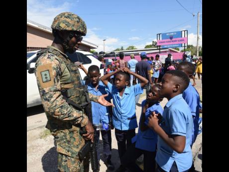 A member of the Jamaica Defence Force speaks with students of Central Branch All-Age School about the role of a soldier.