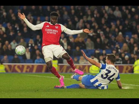 Brighton’s Joel Veltman tackles Arsenal’s Bukayo Saka during the English Premier League soccer match in Brighton, England, on Wednesday. Saka scored as Arsenal won 1-0.