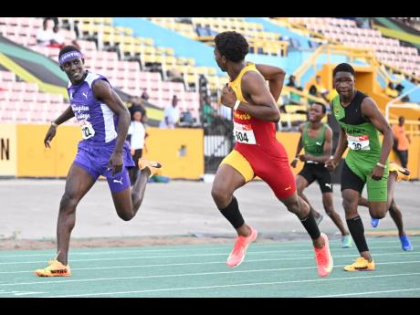 Mark-Daniel Allen (second left) of Wolmer’s Boys’ glances at Kingston College’s Brandon Bennett (left) as he powers to the line to win the boys’ Under-17 110 metres hurdles in 13.57 seconds at the Carifta Trials yesterday.