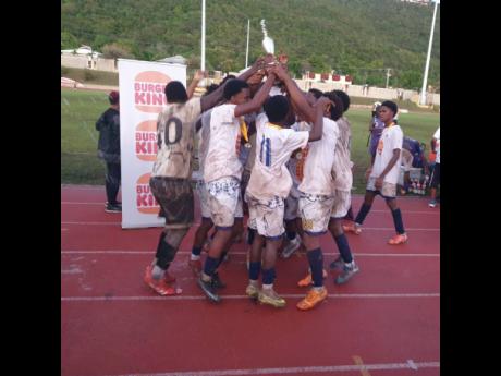 Jamaica College’s Under-16 team celebrate with the Burger King ISSA Under-16 football trophy after a 2-1 win over Kingston College in the final at Stadium East yesterday.